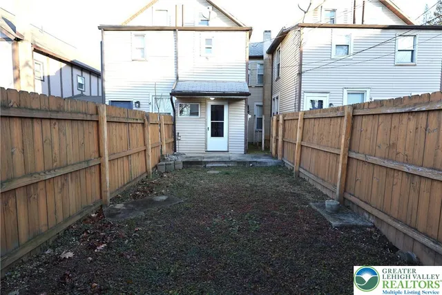 a view of a house with a small yard and wooden fence