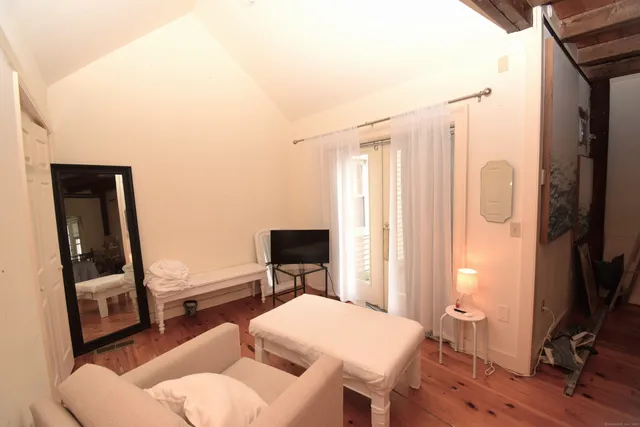 a bedroom with a bed a couch and a flat tv screen on the table