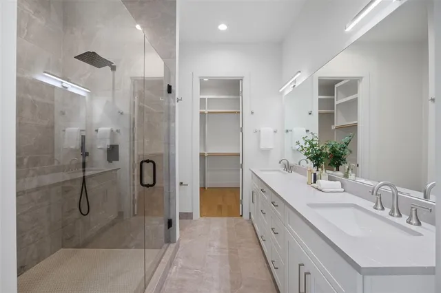 a spacious bathroom with a double vanity sink a large mirror and shower
