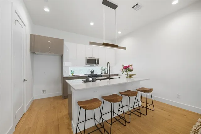 a kitchen with stainless steel appliances a stove a sink refrigerator and a dining table with wooden floor