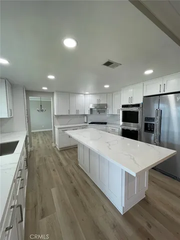 a large kitchen with stainless steel appliances kitchen island a large counter top and a stove top oven