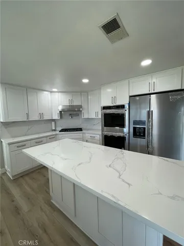 a kitchen with stainless steel appliances kitchen island sink refrigerator and cabinets
