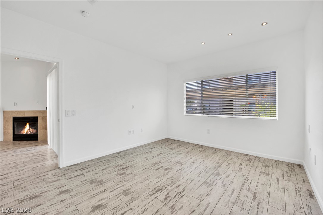8725 West Flamingo Road, Unit 110 Las Vegas, NV 89147 - Photo 9 of 30 A well-lit interior space with a warm fireplace, featuring light-toned flooring.