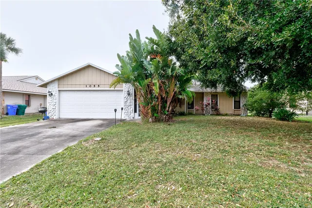 a view of a house with a yard and large tree