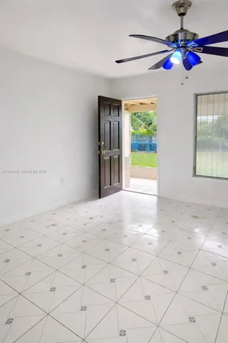 a view of an empty room and window with chandelier fan