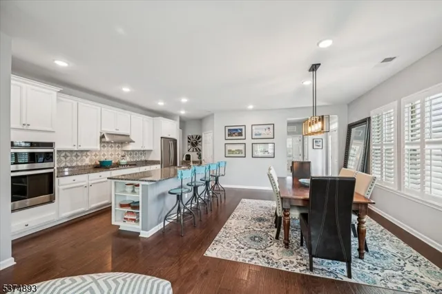 a living room with stainless steel appliances granite countertop furniture wooden floor and a rug