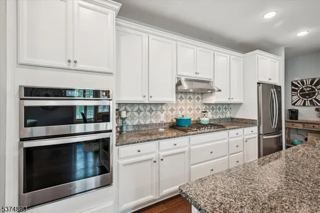 a kitchen with granite countertop white cabinets and stainless steel appliances