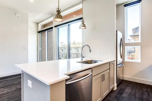 a kitchen with a sink a chandelier and wooden floor