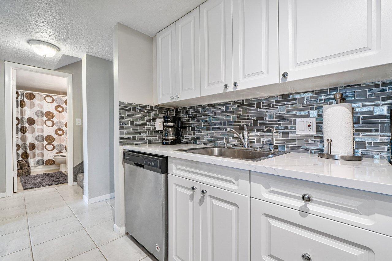 755 Dotterel Road, Unit 1312 Delray Beach, FL 33444 - Photo 9 of 21 a kitchen with stainless steel appliances granite countertop a sink and dishwasher with white cabinets