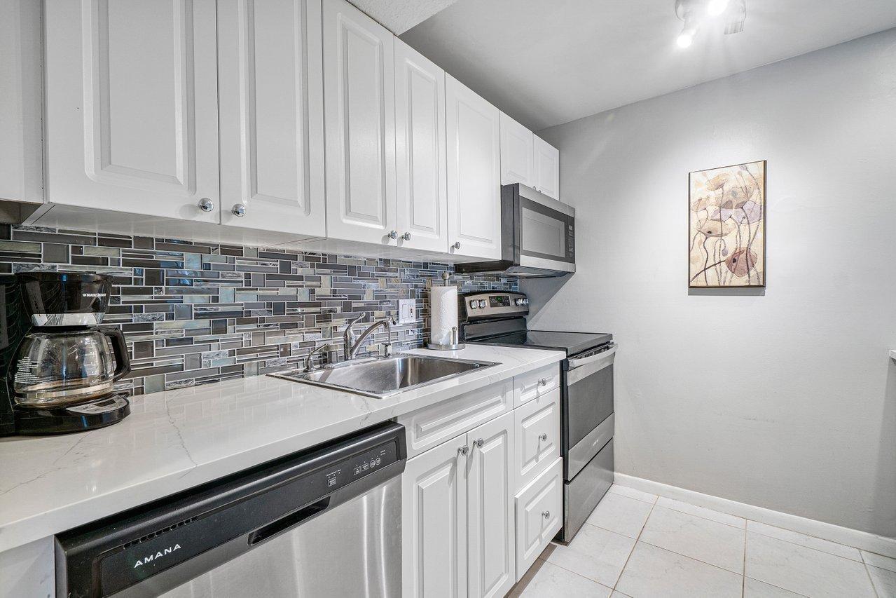 755 Dotterel Road, Unit 1312 Delray Beach, FL 33444 - Photo 10 of 21 a kitchen with stainless steel appliances granite countertop a sink stove and cabinets