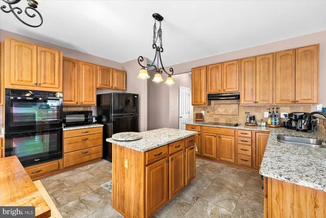 a kitchen with kitchen island granite countertop a sink stove top oven and cabinets