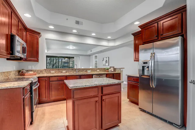 a kitchen with stainless steel appliances granite countertop a refrigerator a sink and a stove