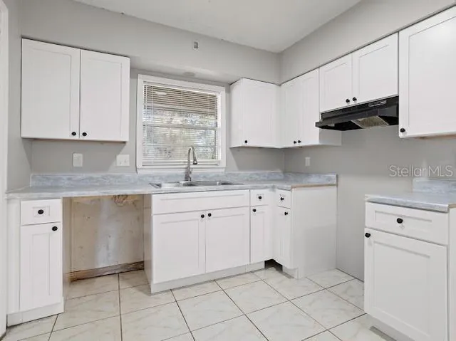 a kitchen with granite countertop white cabinets white stainless steel appliances and sink