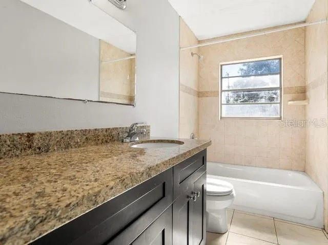 a bathroom with a granite countertop sink a toilet and bathtub