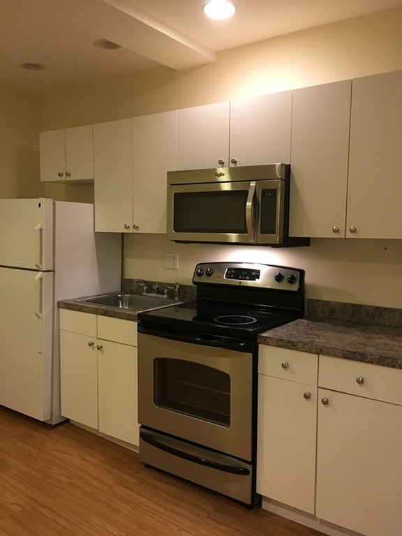 21 Aberdeen Street, Unit A Boston, MA 02215 - Photo 1 of 6 a kitchen with granite countertop a stove a microwave a sink and cabinets