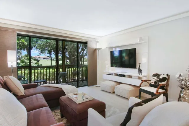 a living room with furniture large flat screen tv and a floor to ceiling window