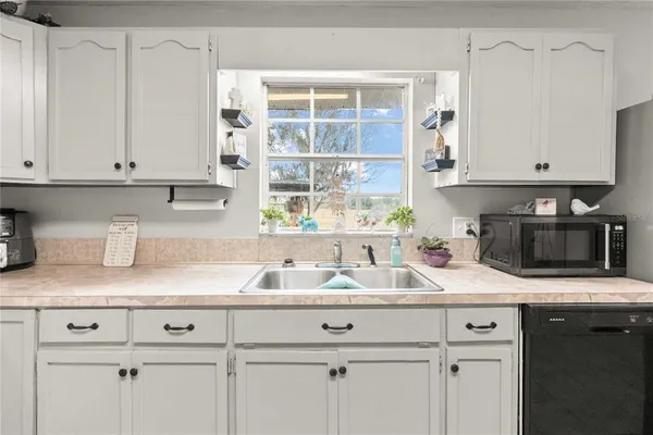 a kitchen with granite countertop a sink and white cabinets