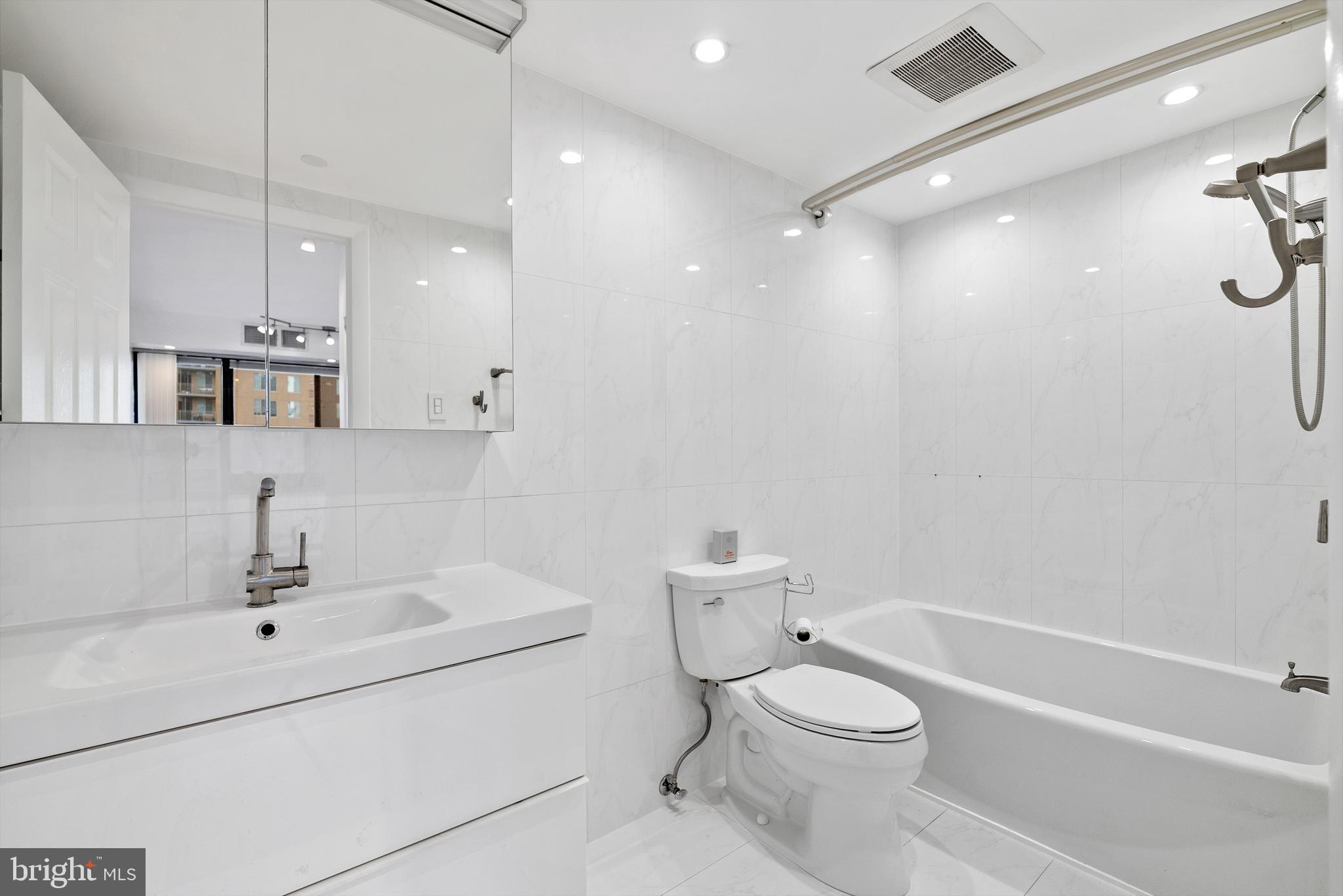 1530 Key Boulevard, Unit 930 Arlington, VA 22209 - Photo 16 of 20 a bathroom with a toilet a sink a mirror and shower