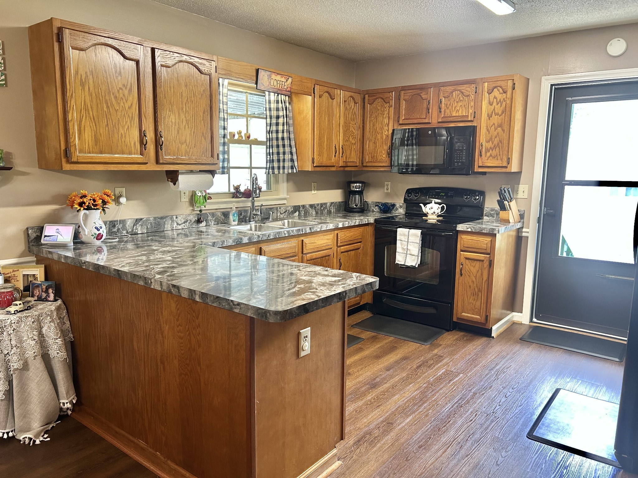 1306 McMahan Street Manchester, TN 37355 - Photo 17 of 48 a kitchen with granite countertop wooden cabinets a stove top oven and stainless steel appliances