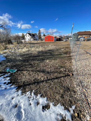 255 West Main Street Mount Pleasant, UT 84647 - Photo 27 of 35 Expansive open lot featuring a red accessory building, partially visible chain-link fencing, gravel border, and a clear blue sky