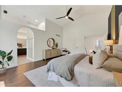 a bedroom with a bed a dresser and potted plants with wooden floor