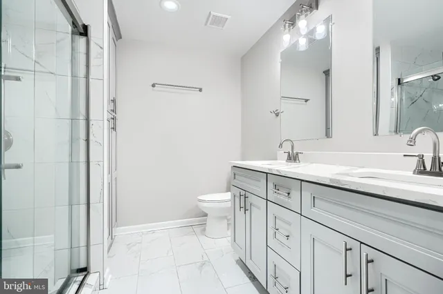 a spacious bathroom with a double vanity sink a toilet and a mirror