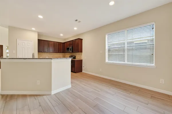 a view of kitchen with stainless steel appliances granite countertop a stove a sink and white cabinets with wooden floor