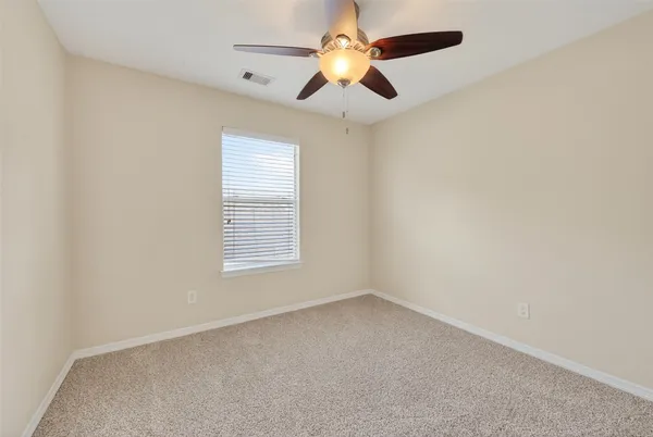 an empty room with a window and a fan