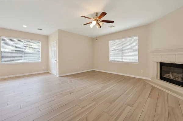 a view of an empty room with a window and wooden floor