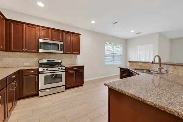 a kitchen with granite countertop a sink and stainless steel appliances