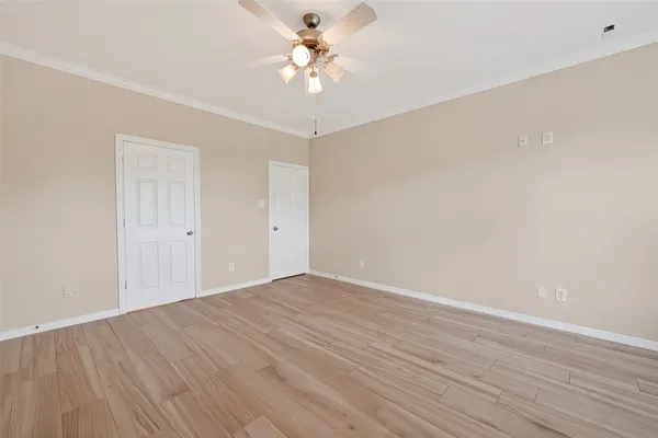 a view of a room with wooden floor and a ceiling fan