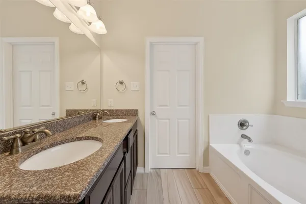 a bathroom with a granite countertop sink a bathtub and a mirror