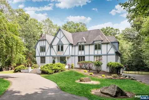 a view of a white house next to a yard with plants and trees