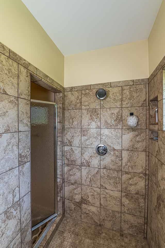 185 Belmont Road Mason, TN 38049 - Photo 28 of 38 Tile-surround shower featuring a glass door, dual shower heads, and an integrated shower niche