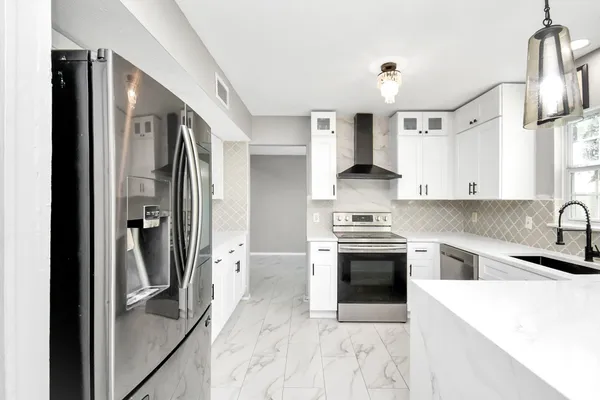 a kitchen with stainless steel appliances granite countertop a refrigerator a stove and a sink