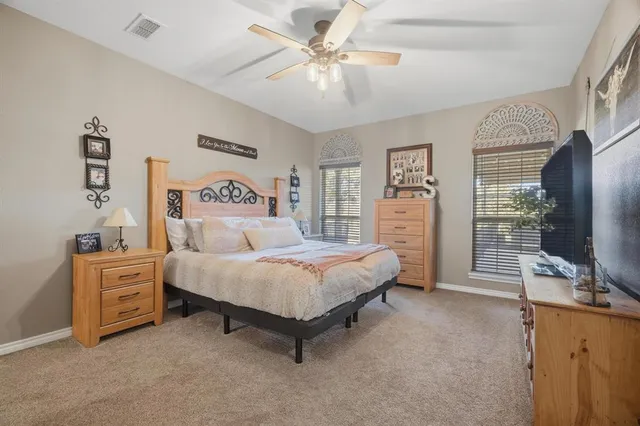 a spacious bedroom with a bed and a flat tv screen on dresser