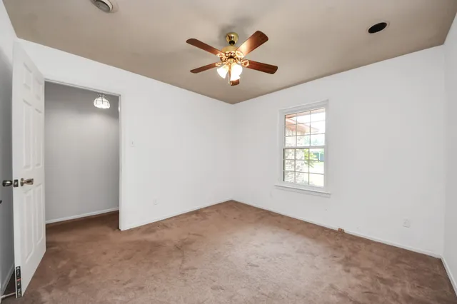 an empty room with a window and a fan