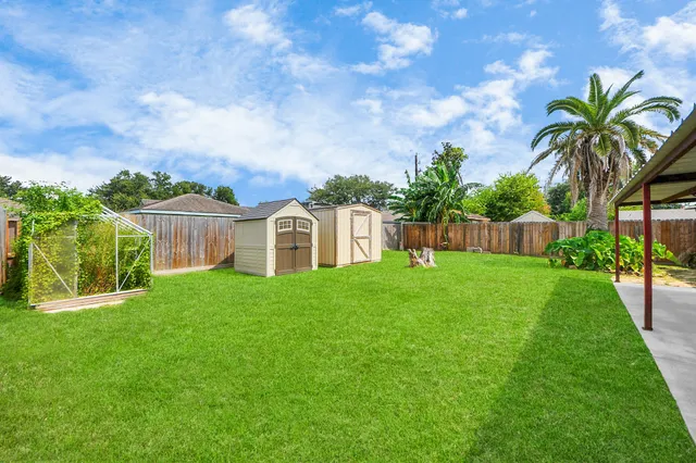 a view of a house with a big yard plants and large trees