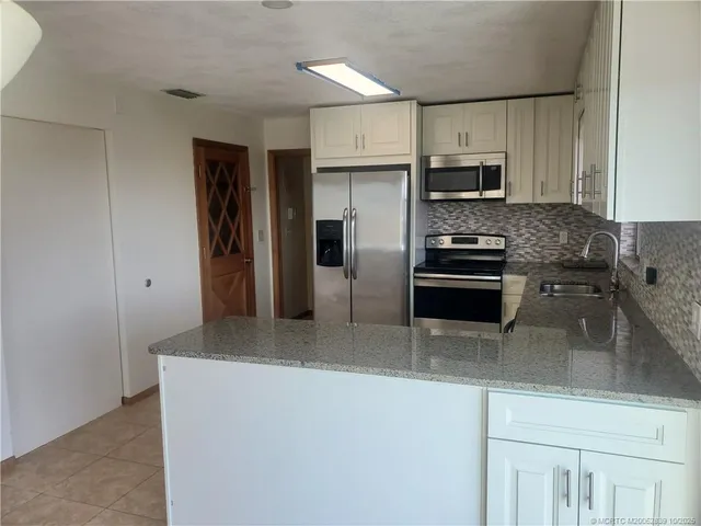 a kitchen with stainless steel appliances a refrigerator a stove a sink and white cabinets