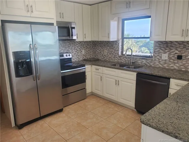 a kitchen with stainless steel appliances granite countertop a refrigerator sink and stove