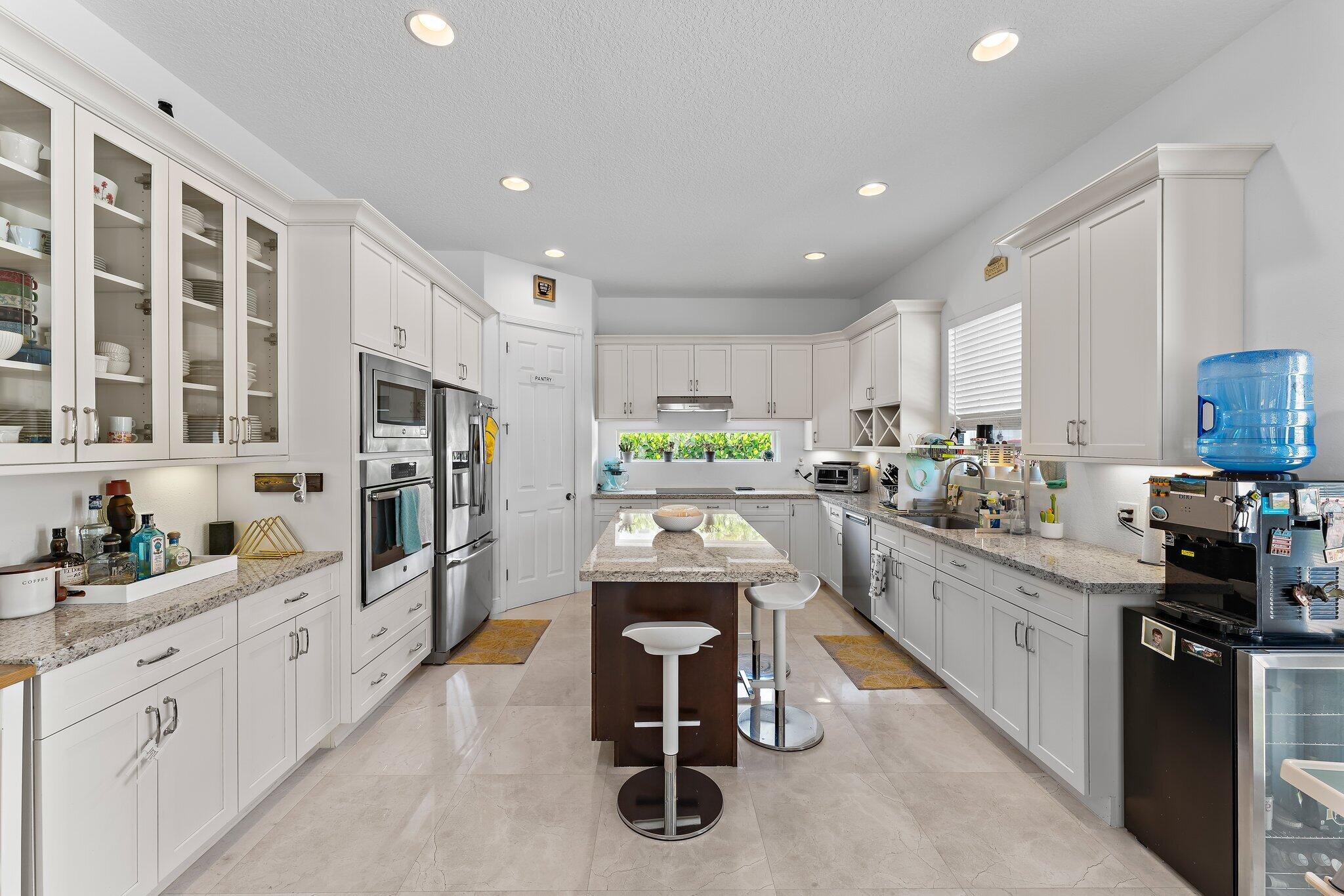 807 Xanadu Place Jupiter, FL 33477 - Photo 13 of 36 a kitchen with white cabinets and stainless steel appliances