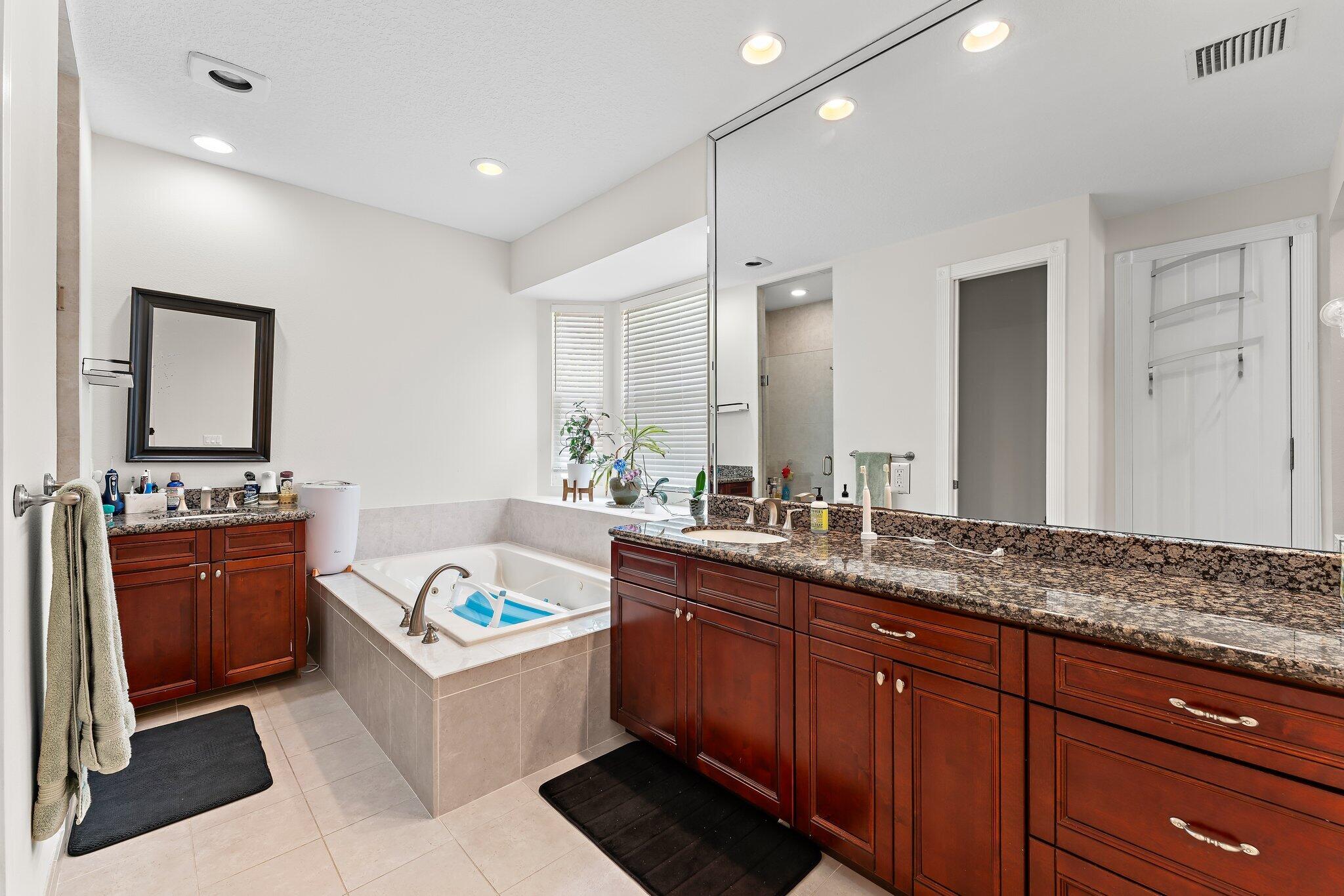 807 Xanadu Place Jupiter, FL 33477 - Photo 21 of 36 a large bathroom with a granite countertop double vanity sink a bathtub and mirror