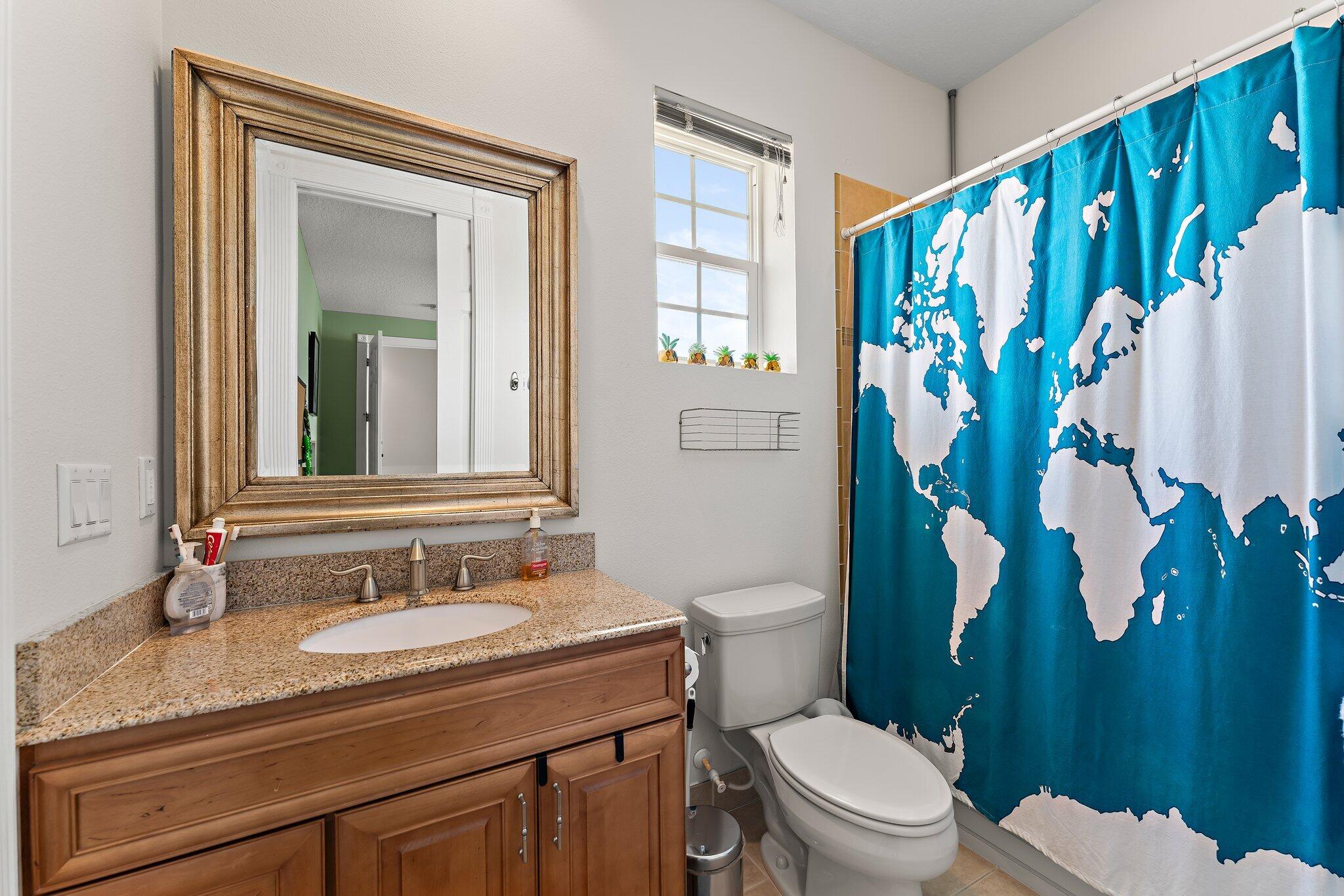 807 Xanadu Place Jupiter, FL 33477 - Photo 25 of 36 a bathroom with a granite countertop sink a toilet and a mirror