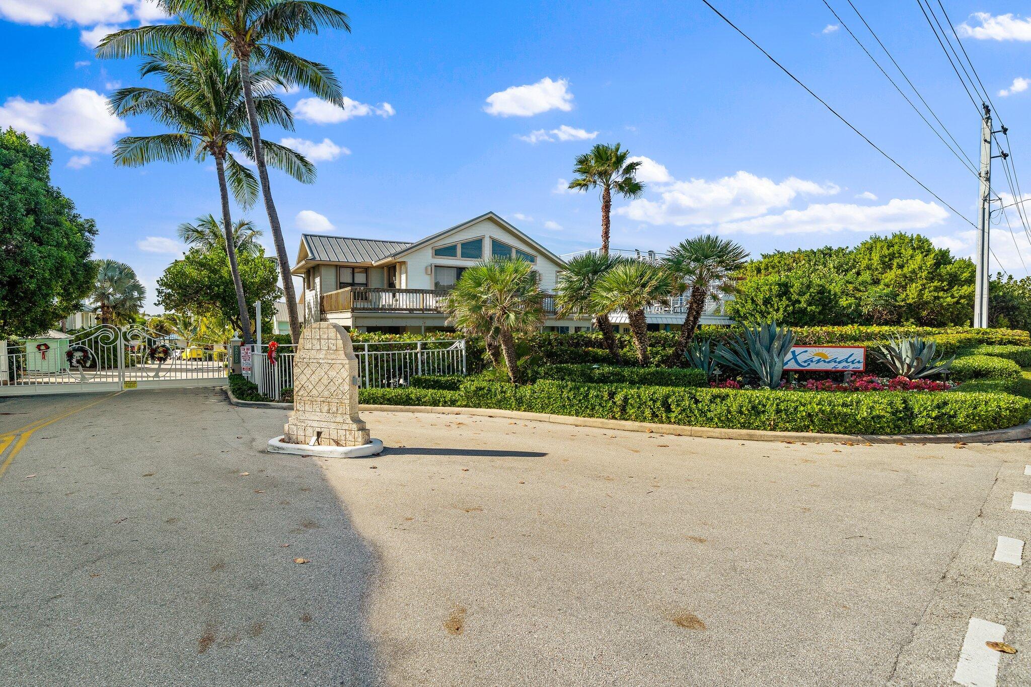 807 Xanadu Place Jupiter, FL 33477 - Photo 3 of 36 a front view of a house with a yard and potted plants