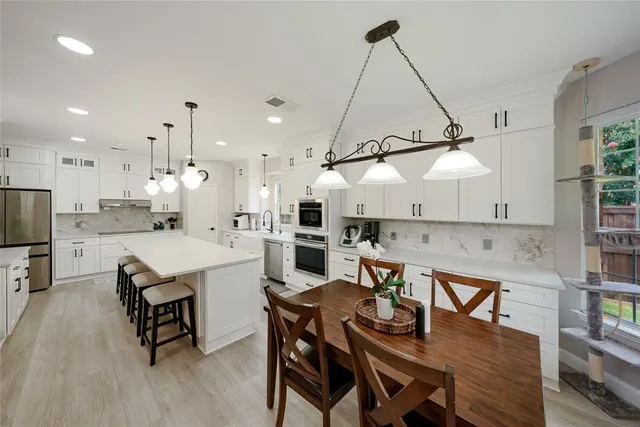 a kitchen with a table chairs microwave and cabinets