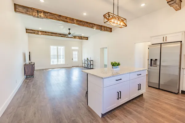 a spacious kitchen with stainless steel appliances granite countertop a refrigerator a sink dishwasher a stove and white countertops with wooden floor