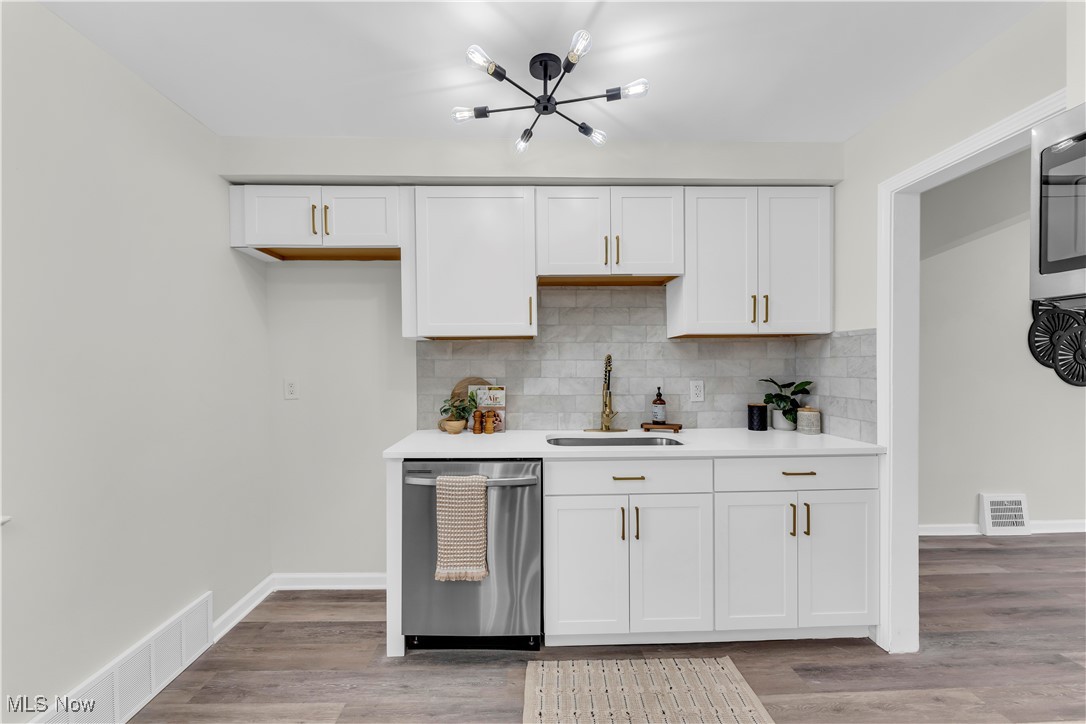 28920 Ridge Road Wickliffe, OH 44092 - Photo 10 of 27 Kitchen with white cabinetry, light wood-type flooring, stainless steel dishwasher, and sink