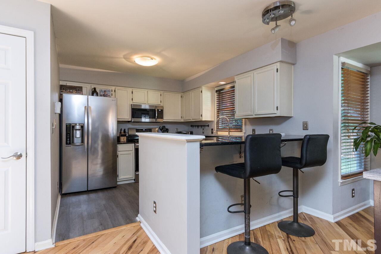 2400 Long And Winding Road Raleigh, NC 27603 - Photo 9 of 29 a kitchen with a refrigerator a stove a sink dishwasher a dining table and chairs with wooden floor