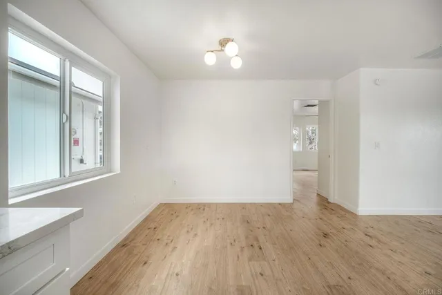 an empty room with wooden floor chandelier and windows
