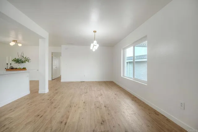 an empty room with wooden floor and chandelier